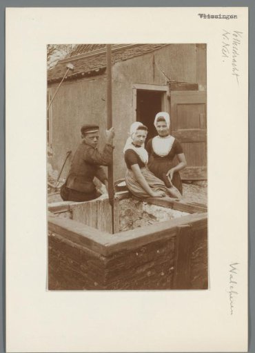 Three children in Walcheren costume beside a well