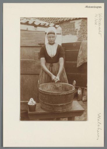 Portrait of an unknown woman in the everyday costume of Walcheren beside a wash tub