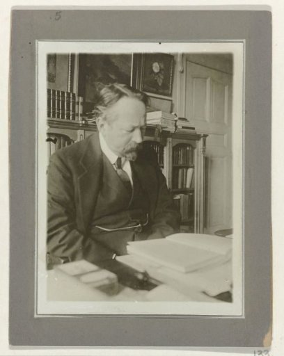 Andries Bonger, seated at a table, reading a book