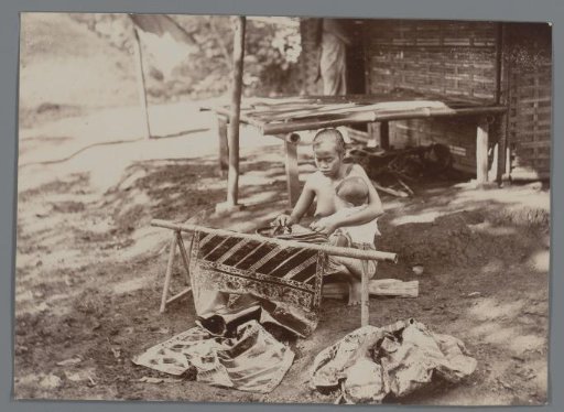 Woman with child making batik, Dutch East Indies