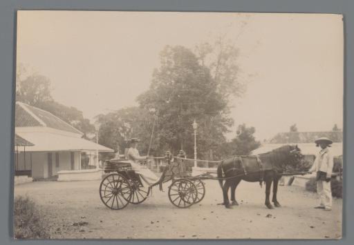 Woman in a carriage with a standing servant, Dutch East Indies