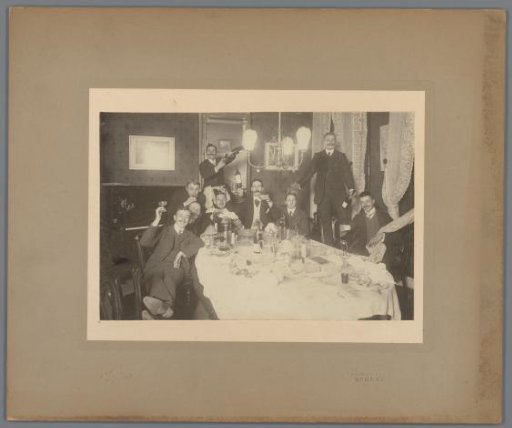 Group portrait of nine unknown young men, probably students, at a set table