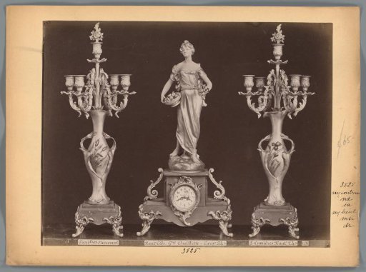Photographic reproduction of two candlesticks and a clock with a female figure holding fruit by V. Constant