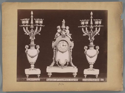 Photographic reproduction of two candlesticks and a clock with two angels