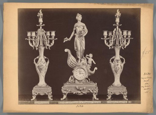 Photographic reproduction of two candlesticks and a clock with a spring figure