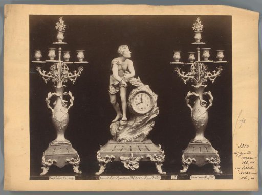 Photographic reproduction of two candlesticks and a clock with a figure holding a sickle