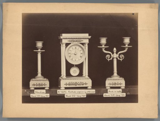 Photographic reproduction of two candlesticks and a regulator clock with columns