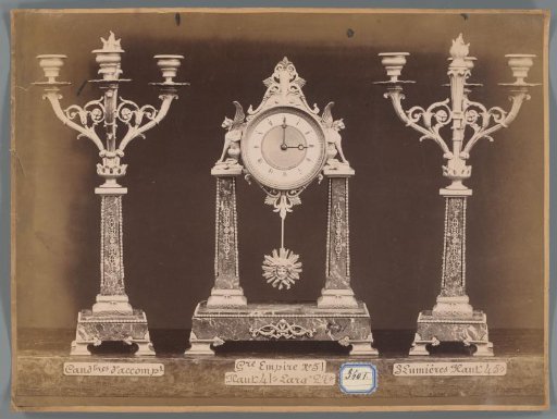Photographic reproduction of two candlesticks and a clock with two griffin figures