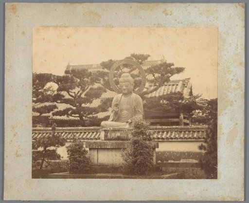 Buddha statue with buildings and trees in the background (possibly) in Japan