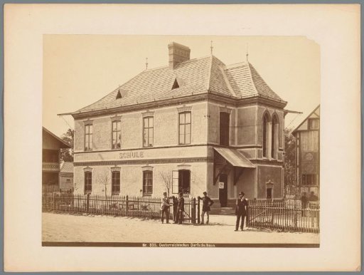 Four men posing in front of an Austrian village school at the 1873 World Exhibition in Vienna