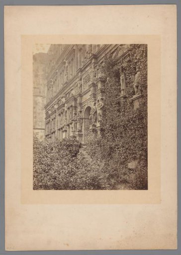 Facade of a building covered with climbing plants and decorated with sculptures of men and women