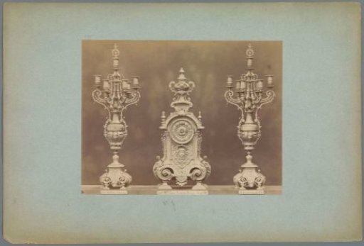 Table clock with two candlesticks, decorated with mask heads