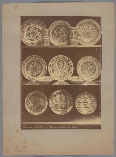 Eleven plates and two cups in a vitrine cabinet
