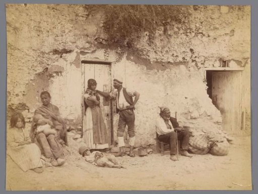 Group portrait of seven unknown men, women, and children in front of a house in the vicinity of Granada