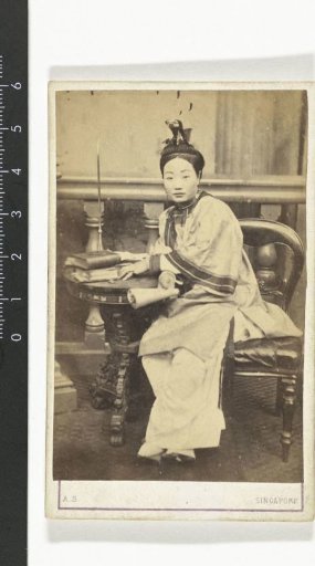 Portrait of a powdered Chinese woman in Chinese dress seated at a table with books