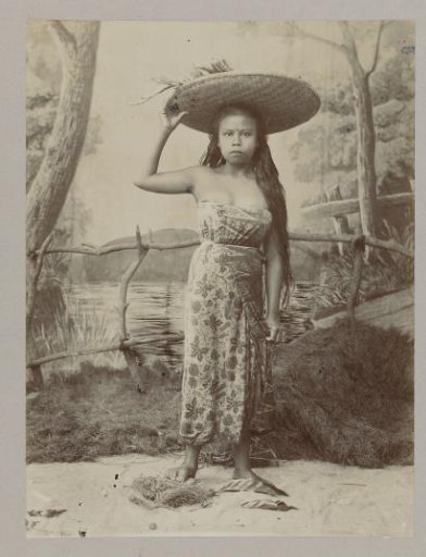 Studio portrait of a girl with a basket on her head in the Dutch East Indies
