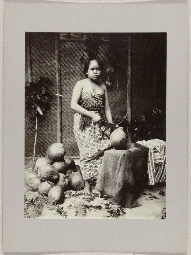 Studio portrait of a girl with coconuts in the Dutch East Indies