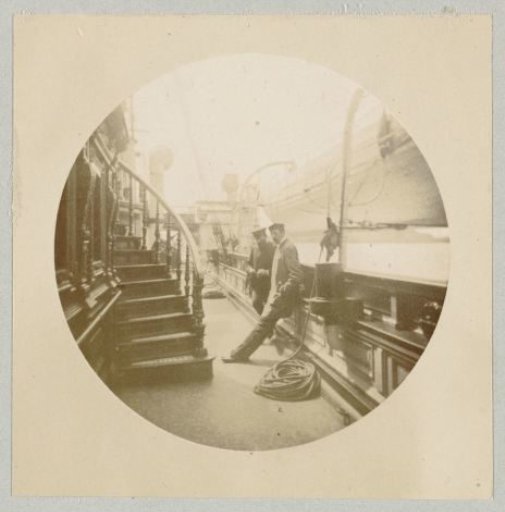 Two men in conversation on the railing of a ship