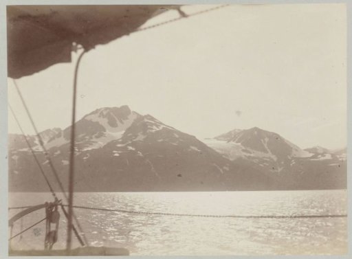 Ship sailing over the sea along snow-capped mountain peaks
