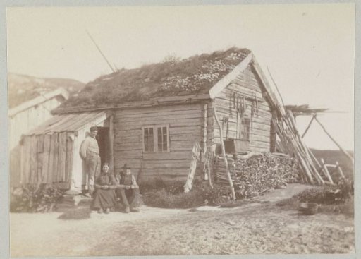 Family in front of their wooden house with roof vegetation