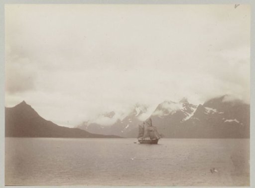 Ship at sea against the background of snow-capped mountain peaks