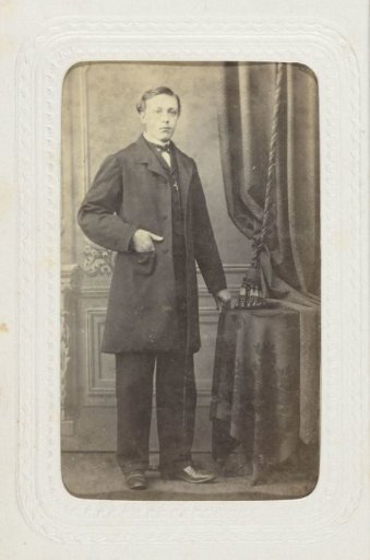 Studio portrait of a man standing at a table before a backdrop