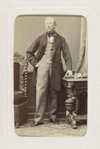 Studio Portrait of a Man Posing at a Table with One Hand in His Pocket