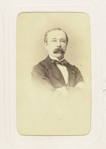 Studio portrait of a man with a mustache, dressed in a dark suit