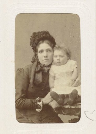 Studio portrait of a woman dressed in black with a baby on her arm