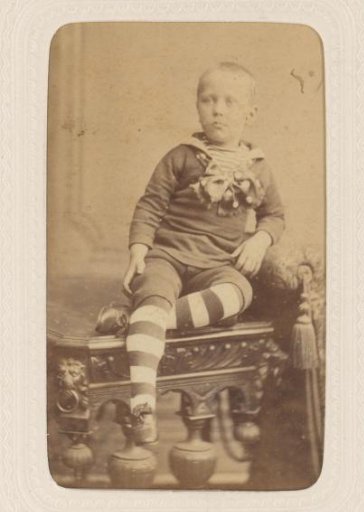 Studio portrait of a boy on a table, dressed in a sailor suit