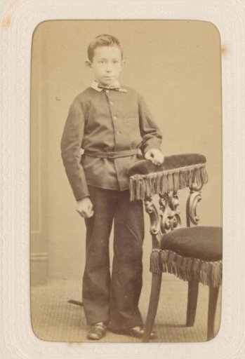 Studio portrait of a boy by a chair