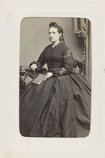 Studio Portrait of a Woman Sitting on a Chair in a Long Black Dress