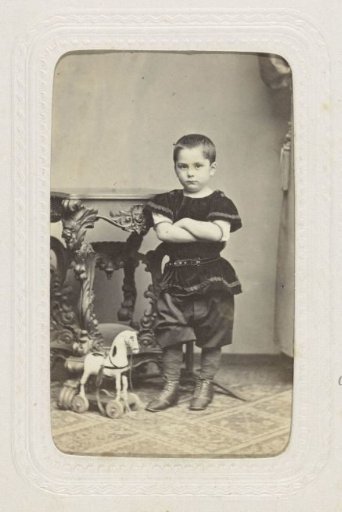 Studio portrait of a boy with a wooden horse at a table