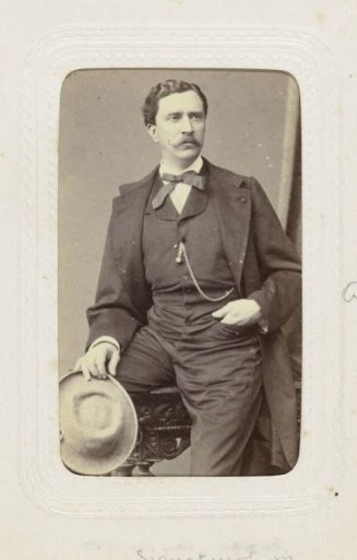 Studio portrait of a man with a mustache and a hat in his hand