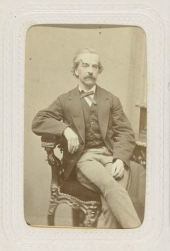 Studio portrait of a man with a mustache in an armchair