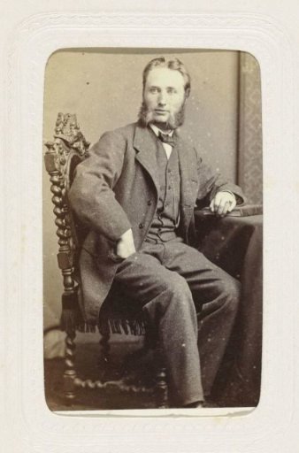 Studio portrait of a seated man with large sideburns