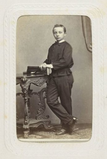 Studio portrait of a standing boy by a table