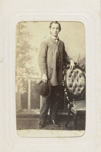 Studio portrait of a young man with a hat in his hand