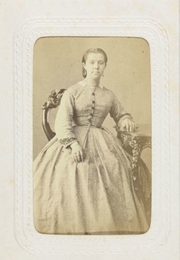 Studio portrait of a woman at a table in a long, full dress