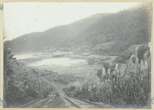 Railway in hilly landscape near the sea in French Indochina
