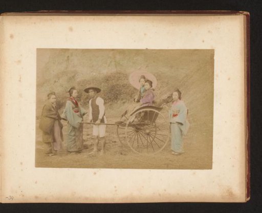 Two Japanese women in a rickshaw pulled by a man, with three other women nearby