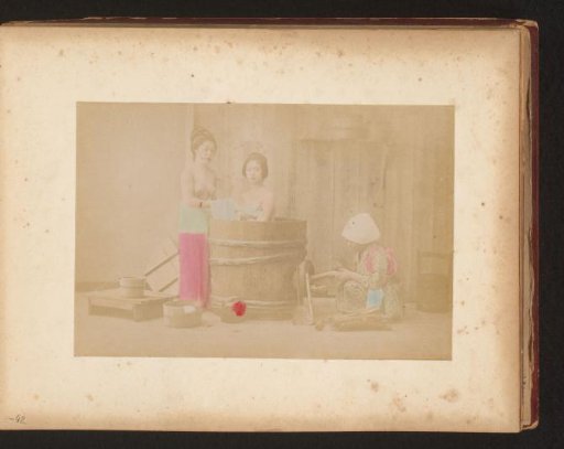 Two Japanese women bathing, a servant lighting the fire
