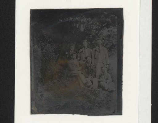 Group portrait of men with caps in a forest or park
