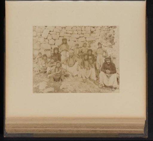 Group of Men and Children Around a Water Pipe in Front of a Stone Wall