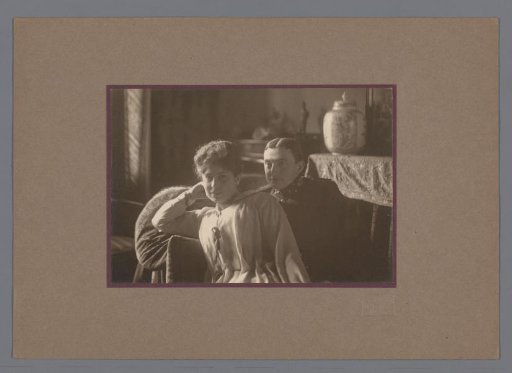 Portrait of a man and woman, seated on a bench, in an interior
