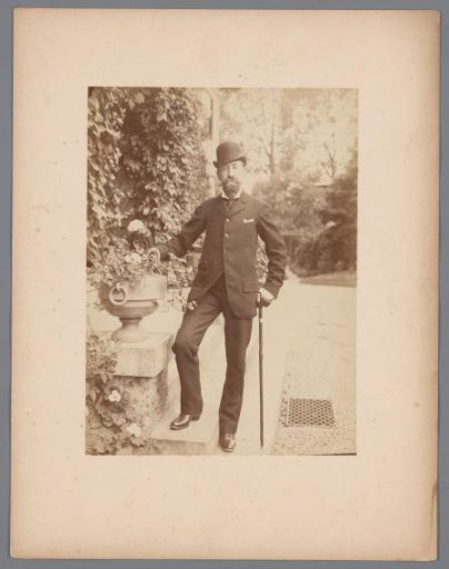 Portrait of a standing man in a garden or park, with a walking stick
