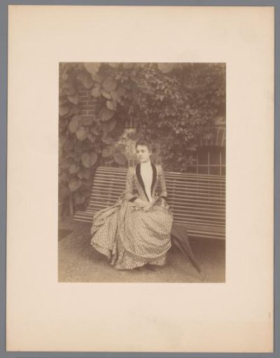 Portrait of a seated young woman in a garden or park
