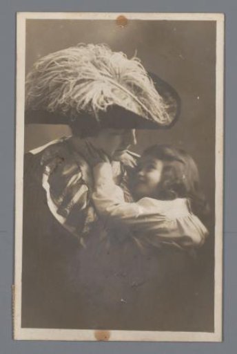 Postcard with a photograph of a mother wearing a hat and a child in her arms