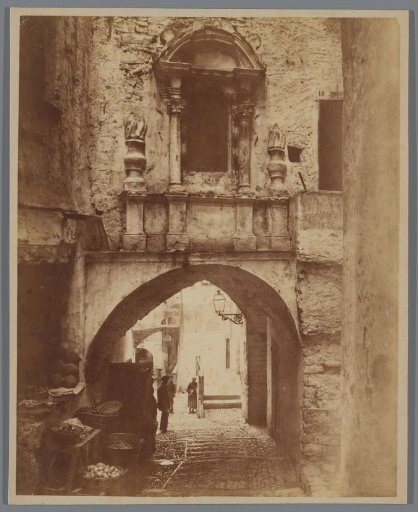 Street in Southern Europe or North Africa with fruit and vegetable sales under an archway