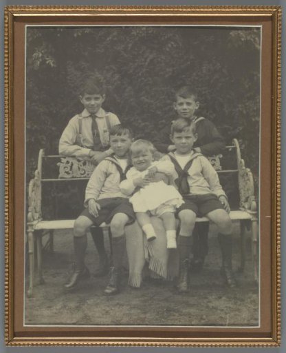 Group portrait of five unknown children on and around a bench